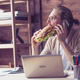 man eating sandwich at desk
